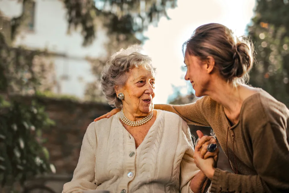 Woman sitting beside an older family member and holding her hand
